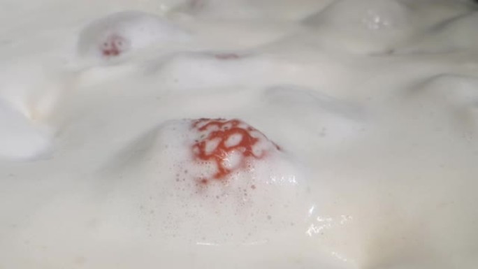 旋转成熟的草莓，上面覆盖着厚厚的奶油。相机旋转360度，特写。
