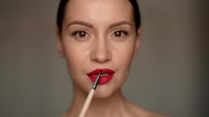 女人用刷子涂红色唇膏