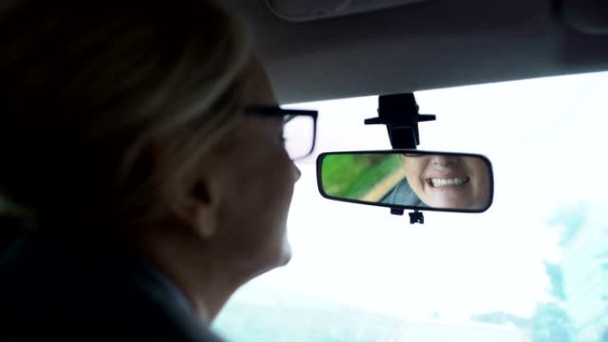 女人看她的牙齿在汽车后视镜，牙龈和牙齿敏感