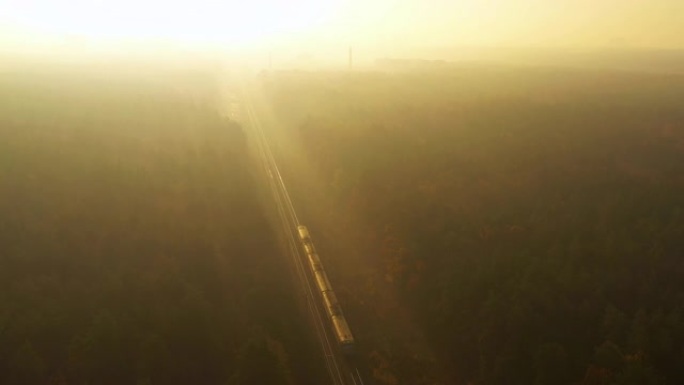 火车穿过秋天的雾林，走向黎明。4k无人机视图