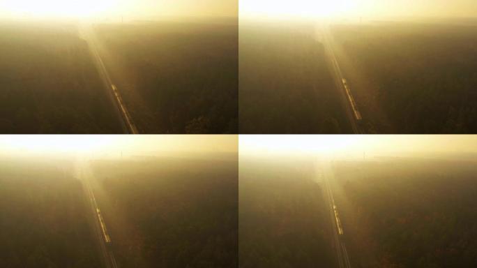 火车穿过秋天的雾林，走向黎明。4k无人机视图