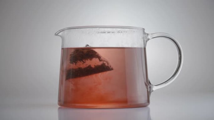 将茶包浸泡在玻璃罐中。孤立，在灰色背景上。生态产品。天然饮料制作概念。