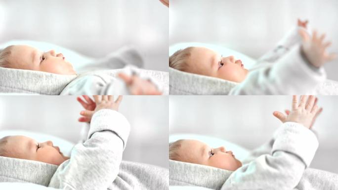 特写可爱的小宝宝躺在床上拍手重复妈妈手臂一起玩侧视