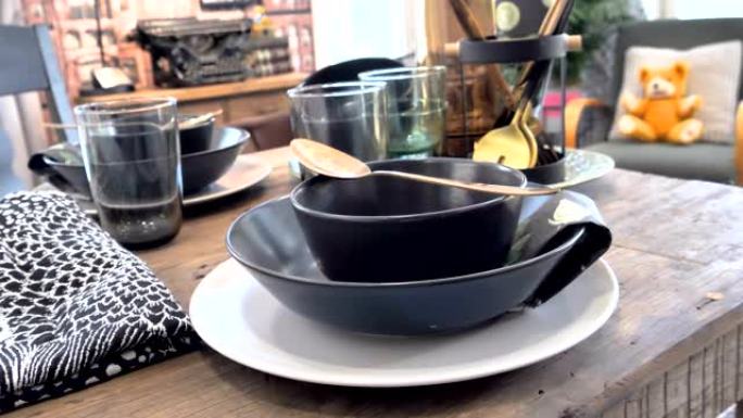 小木桌上盘子上面的黑碗