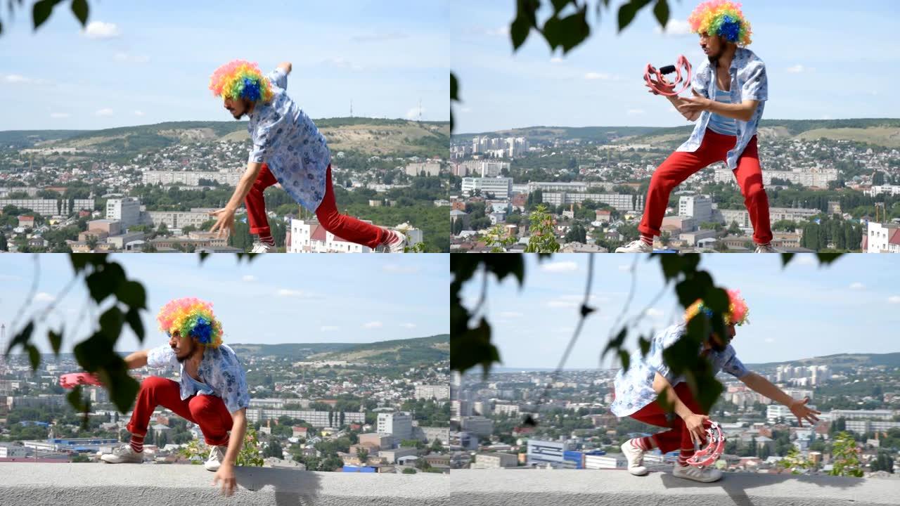 疯狂的哑剧手鼓在栏杆上跳舞。小丑在城市背景下的有趣动作。