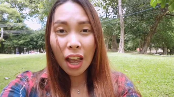 亚洲妇女在公园里用手机与聋哑朋友聊天，拿着智能手机进行视频聊天。