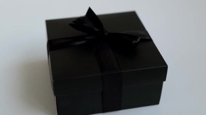 节日礼物在黑色美丽的盒子在白色背景。优雅的黑色节日盒子，带丝带。