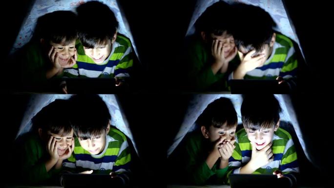 小男孩晚上在数字平板电脑上看书