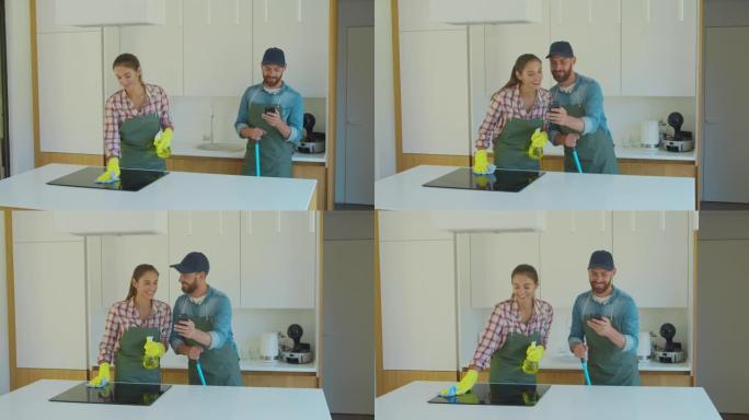 男人和女人作为uniiform的专业清洁工，在厨房工作期间玩得开心