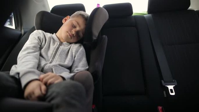 度假期间公路旅行时，坐在汽车安全座椅上的疲惫男孩睡觉