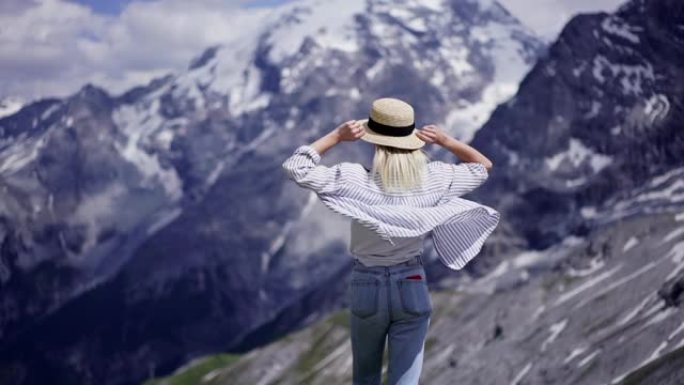 年轻的时髦女孩站在高海拔的山中举手，享受风和自由