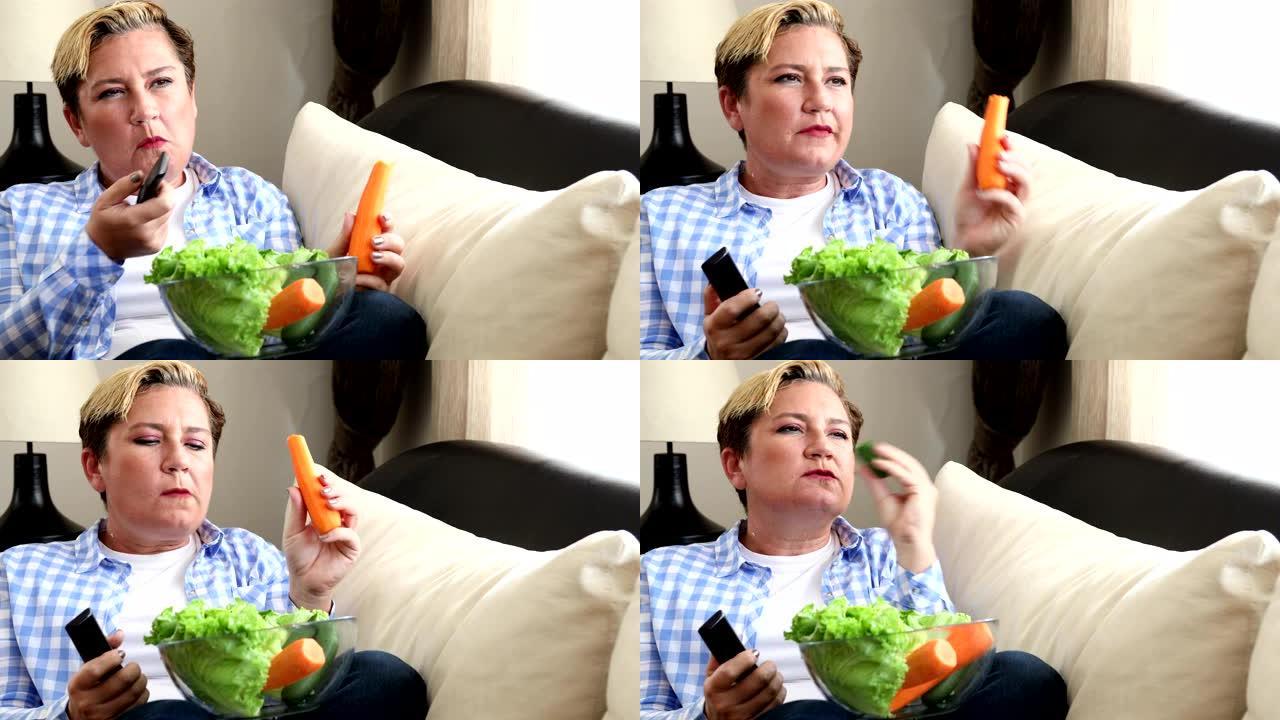 女人吃新鲜的减肥食品和在家里看电视的肖像