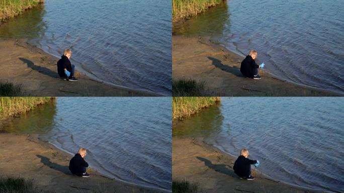 一个小男孩帮助从海滩和河里的水中收集垃圾。