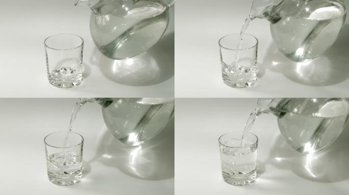 将来自jag的新鲜纯净水倒入白色背景的透明玻璃中。健康和饮食概念。水填充到透明玻璃中。慢动作镜头