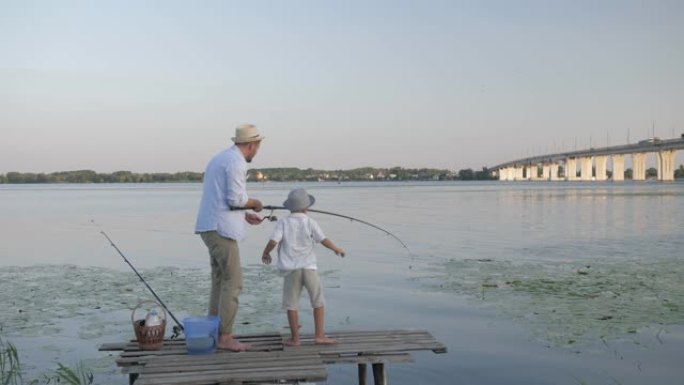 童年快乐，慈爱的爸爸在乡下暑假和他亲爱的儿子在河边的码头钓鱼