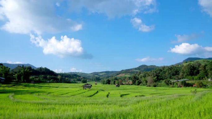 泰国炎热的夏日，4k延时拍摄在晴朗的蓝天中移动的白云，阳光穿过山脉，稻田和小小屋