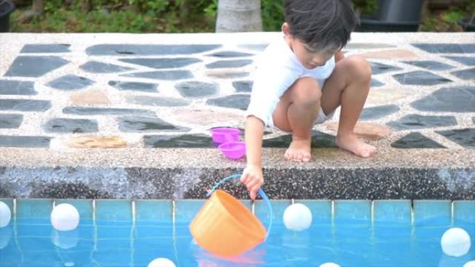 亚洲男孩儿子儿童在游泳池边玩台球玩具快乐学习生活与家庭娱乐学习和玩耍。