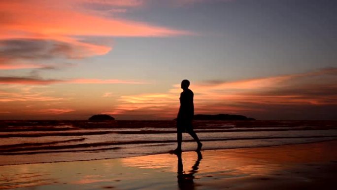 日落时站在海滩上的剪影人