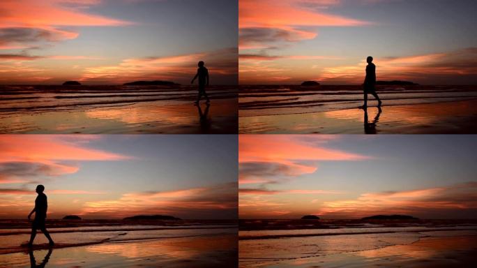 日落时站在海滩上的剪影人