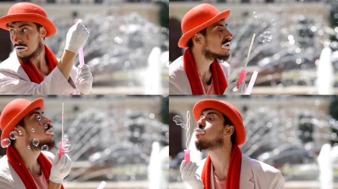 哑剧在喷泉的街道上吹肥皂泡。小丑在城里展示了一幅素描。