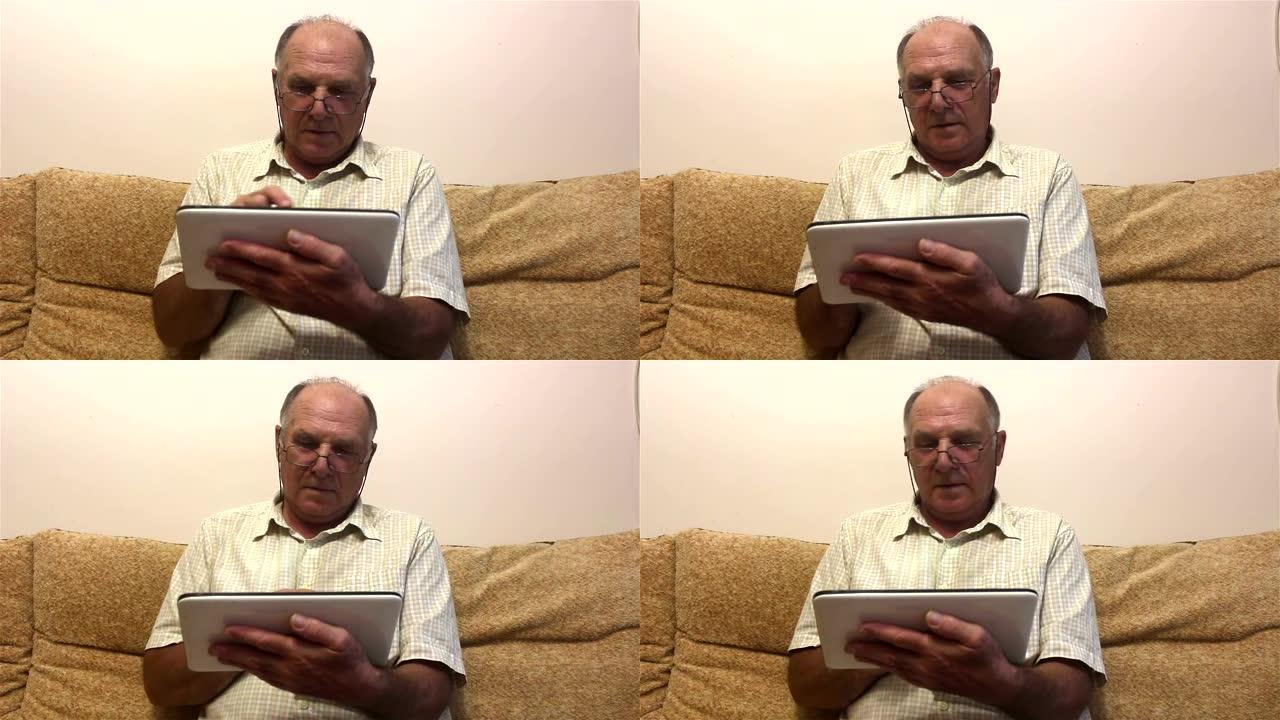 一位老人坐在家里的沙发上，在平板电脑上工作。