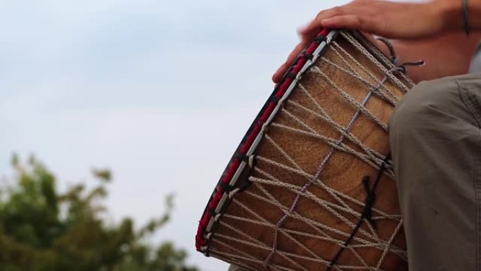 一名男子在蓝天下演奏非洲djembe鼓。创造力、休息和放松。民族乐器逆天作为创意飞行的概念。