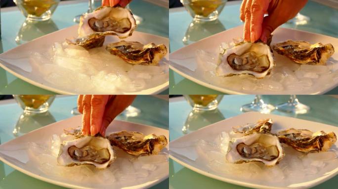 女人的手把开着的牡蛎放在加冰的盘子里。