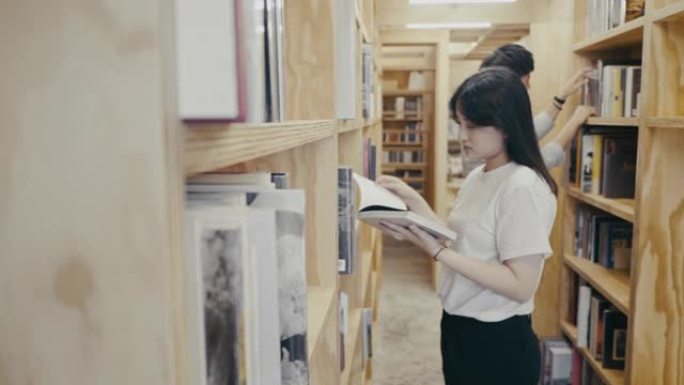 年轻的亚洲大学生在图书馆寻找书籍 (慢动作)