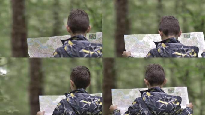 森林中的旅行男孩看着地图，下雨的天气