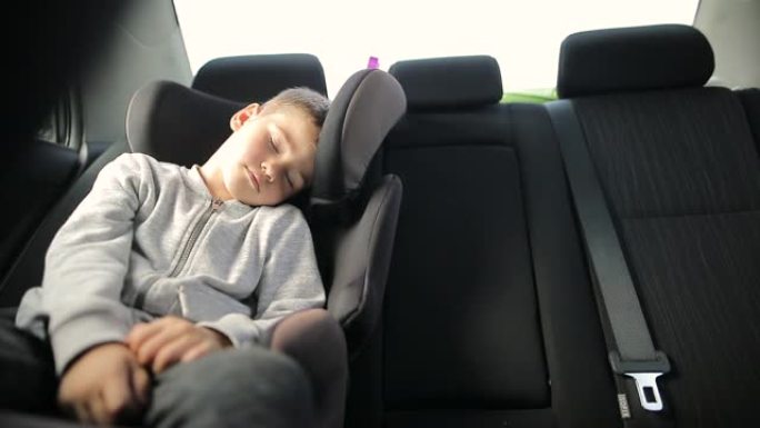 度假期间公路旅行时，坐在汽车安全座椅上的疲惫男孩睡觉