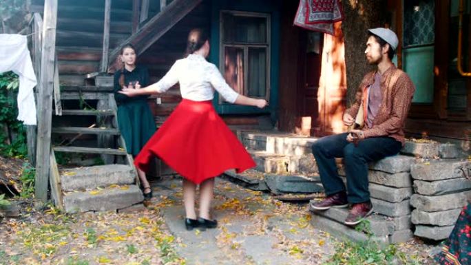 一个穿着红色裙子的女人在音乐中跳舞-一个男人在玩balalaika-另一个女人在拍手