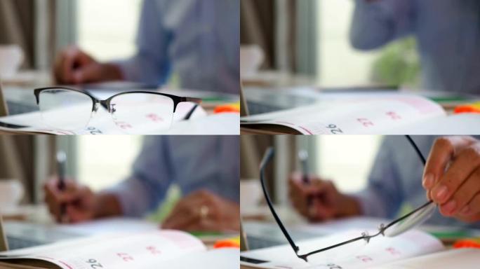 计划者日程日记本上的选择性聚焦手拾音器眼镜，带有淡色商人背景