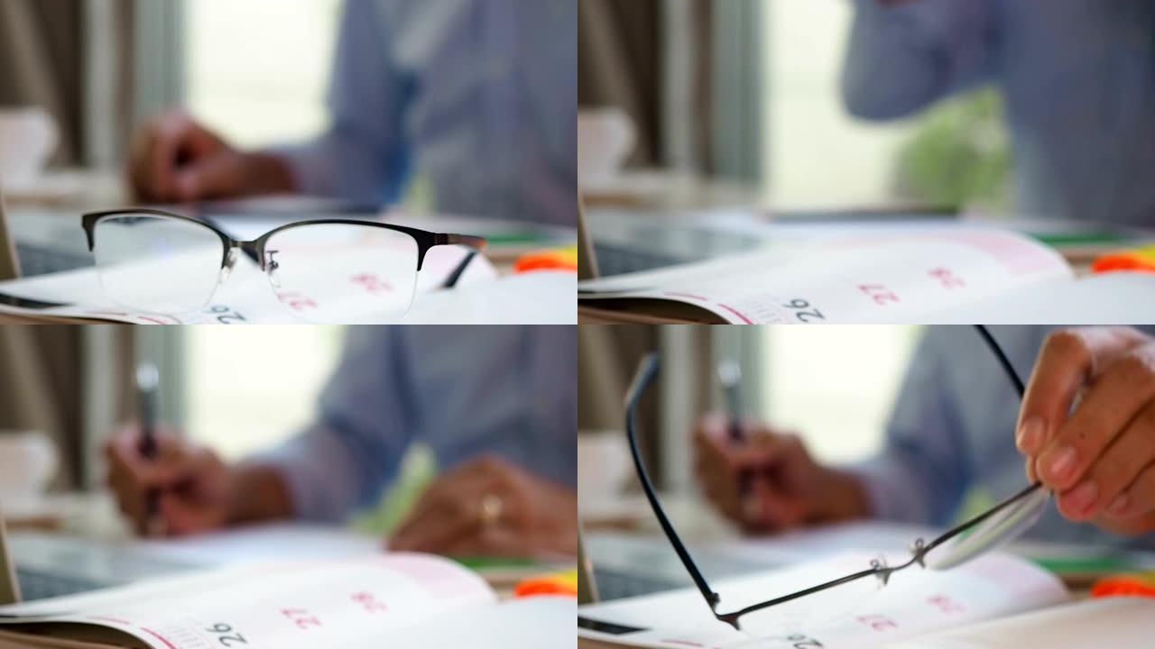 计划者日程日记本上的选择性聚焦手拾音器眼镜，带有淡色商人背景