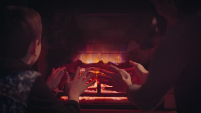 妈妈和儿子在壁炉旁暖手。