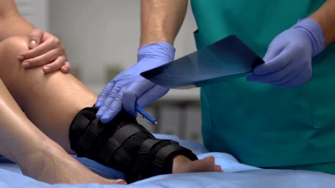 创伤专家向脚踝包裹，医疗保健患者解释x射线结果