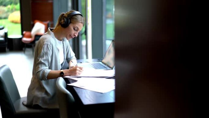 女商人在蓝牙电子耳机中听力教程信息，同时在纸上编写课程信息