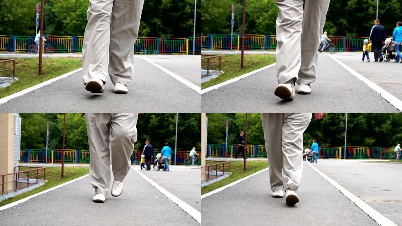 穿着白鞋的男人腿在户外的瓷砖路上行走