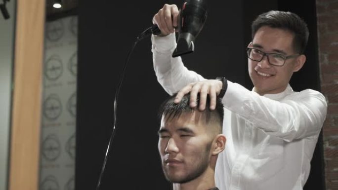 理发师用吹风机干燥亚洲客户。