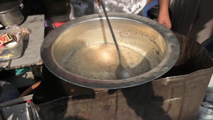 一个印第安人在混乱的印度新德里的一条小巷里准备著名的柴茶的慢动作视频。