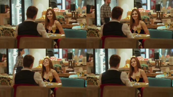 在一家昂贵的餐厅吃晚餐，一个漂亮的女孩在餐桌旁说话和微笑。一对恋人正在吃饭。肖像视图。