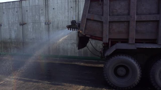 特写。汽车在纳霍德卡 (Nakhodka) 的煤炭贸易港口倒入干净的煤尘中弄脏的沥青。湿洗。