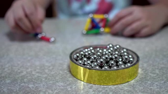 小孩子在室内玩许多彩色磁铁玩具和铁球。重点是铁球。