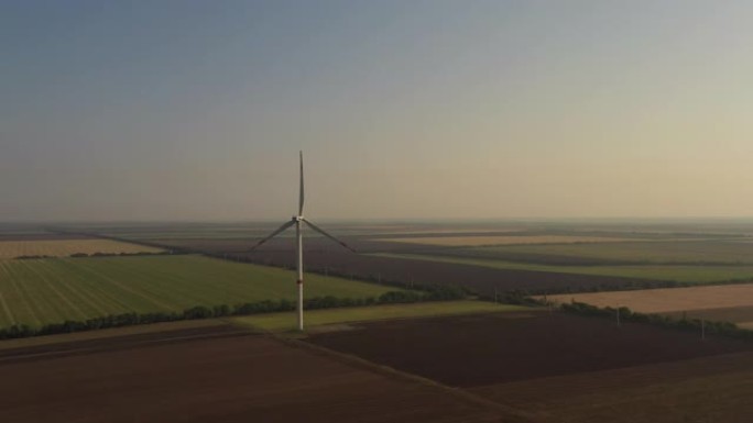 在早晨的天空背景下，在阳光的照射下，在农田上的4k风电场。生态与绿色能源概念