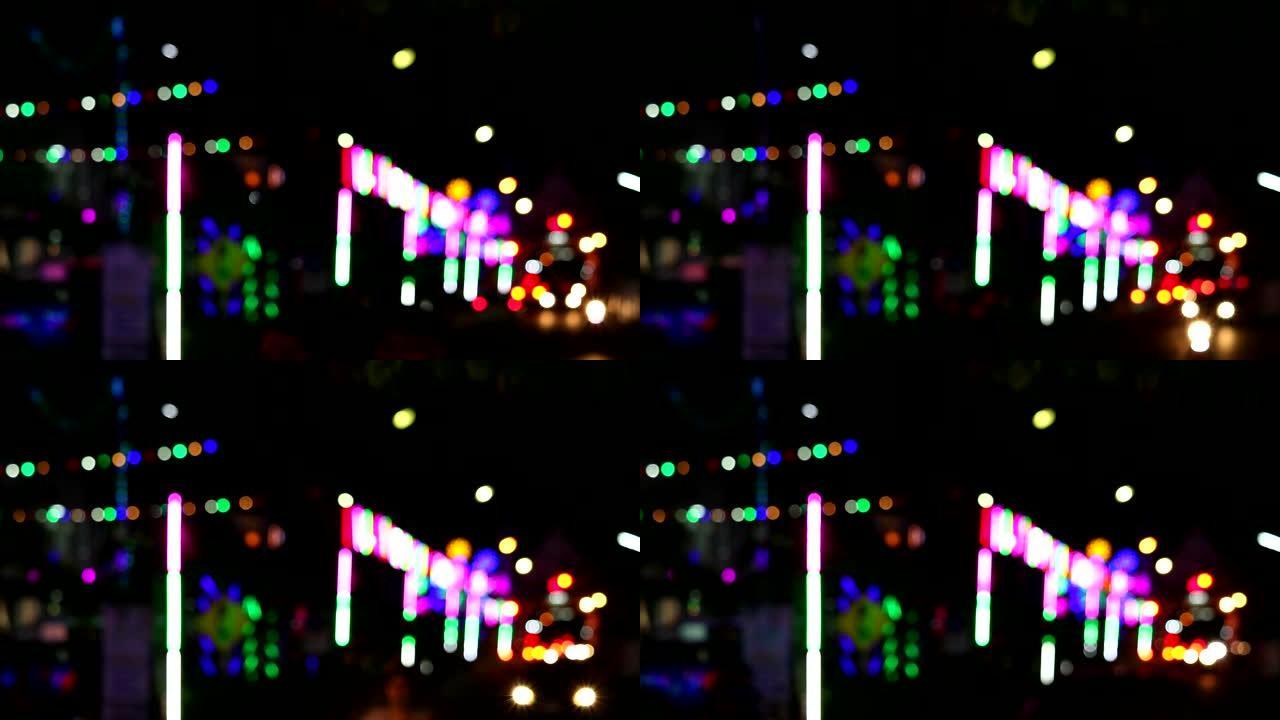 夜市集市上模糊霓虹灯和轮廓人物和车辆的多彩