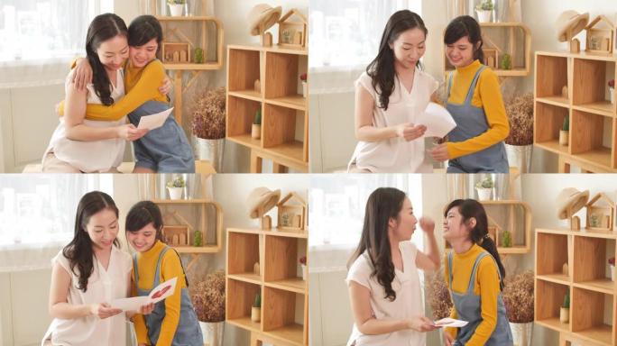 快乐的亚洲家庭妈妈和十几岁的女儿拥抱在一起，在家里有自然阳光的房间里阅读卡片。秀爱心，母亲节快乐理念