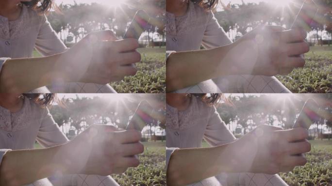 公园里日出时，女人的手触摸屏智能手机