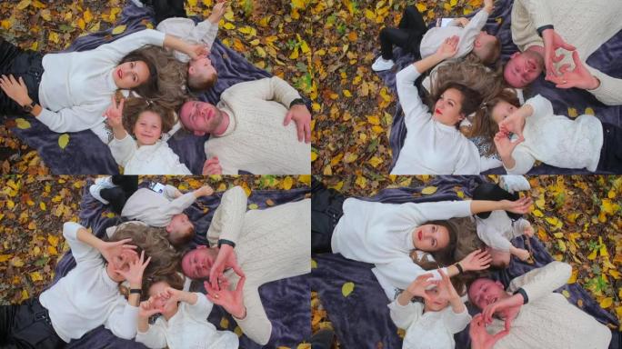 一个友好开朗的家庭躺在城市公园的秋叶上。