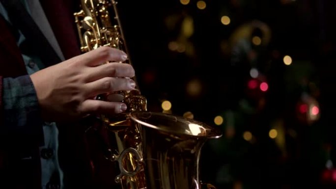 萨克斯管演奏者以慢动作演奏萨克斯管。圣诞树背景
