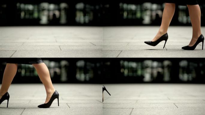 穿着高跟鞋的女性腿在城市街道上行走。穿着高跟鞋的年轻女商人的脚在城市里。女孩踏上工作岗位。慢动作特写