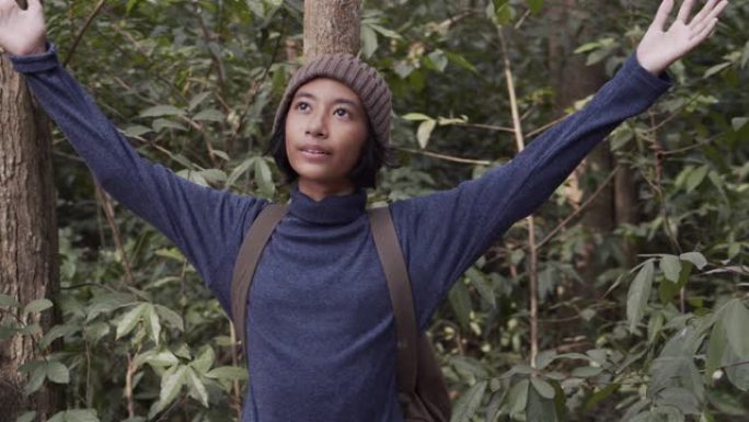 中枪。亚洲小女孩举起她的手，微笑着快乐地享受着早晨在森林里的大自然。概念自由